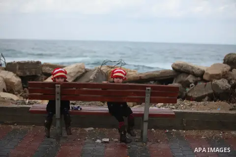 Palestinian girls sit at the seaport near the coast of Gaza city during a rainy day, February 18, 2015. Photo by Ashraf Amra