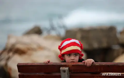 A Palestinian girl sits at the seaport near the coast of Gaza city during a rainy day, February 18, 2015. Photo by Ashraf Amra