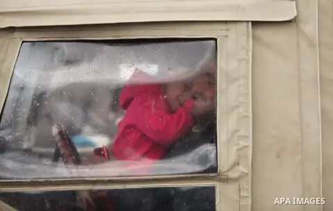 A Palestinian man plays with his daughter in a car at the seaport near the coast of Gaza city during a rainy day, February 18, 2015. Photo by Ashraf Amra