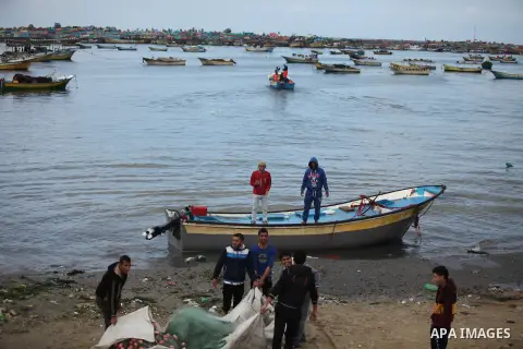 Palestinian fishermen ride their boat during a rainy day at the seaport near the coast of Gaza city, February 18, 2015. Photo by Ashraf Amra