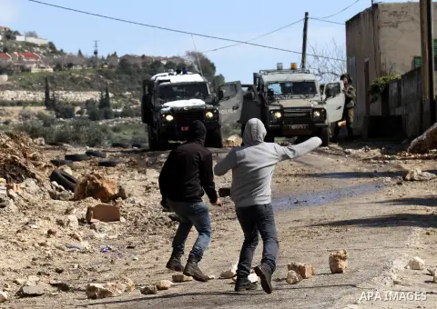 Palestinian protesters throw stones at Israeli security forces during clashes in a protest against the expropriation of Palestinian land by Israel in the West Bank village of Kfar Qaddum, near the northern city of Nablus...
