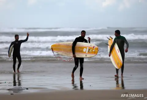 Palestinian youths surf in the Mediterranean Sea off the coast of Gaza City, during rainy weather, Feb. 21, 2015. A heavy winter storm descended on parts of the Middle East. Photo by Yasser Qudih