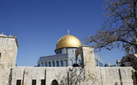 Palestinians sit in front of the Dome of the Rock at the al-Aqsa mosque compound after a snowstorm in Jerusalem's old city, February 22, 2015. Some parts of Israel were covered with snow early Friday amid a heavy winter...
