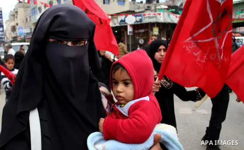 A Palestinian woman carries her son during a rally marking the 46th anniversary of the founding of the Democratic Front for the Liberation of Palestine (DFLP), in Rafah in the southern Gaza Strip February 23, 2015. Photo...