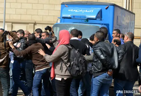 Egyptians gather arround a car belong to the Egyptian television after it was broken by students who are support ousted President Mohamed Morsi and the Muslim Brotherhood during protest against the military rule, in Cair...