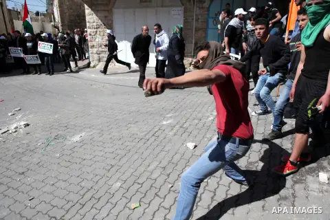 A Palestinian protester throws stones towards Israeli soldiers during clashes in a protest demanding the reopening of Shuhada Street in the West Bank city of Hebron on February 27, 2015. Photo by Mamoun Wazwaz