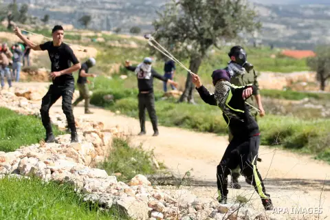 Palestinian protesters use sling shots to hurl stones at Israeli security forces during clashes following a demonstration against Jewish settlements in the West Bank village of Bilin, west of Ramallah, February 27, 2015....