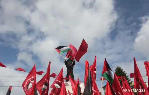A Palestinian supporter of the Popular Front for the Liberation of Palestine (PFLP) hold flags as he take part a protest demanding for reconstruction of houses which were destroyed during the recent Israeli war, in Gaza...