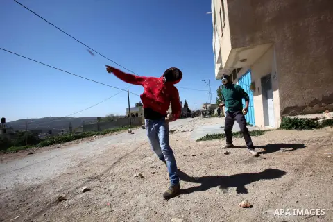 A Palestinian protester throws stones at Israeli security forces during clashes following a protest against the expropriation of Palestinian land by Israel in the West Bank village of Kafr Qaddum, near the northern city...