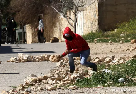 A Palestinian protester throws stones at Israeli security forces during clashes following a protest against the expropriation of Palestinian land by Israel in the West Bank village of Kafr Qaddum, near the northern city...