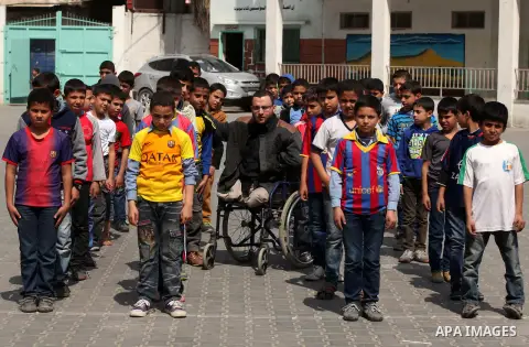 Wheelchair-bound Palestinian student teacher Ahmed al-Sawaferi, 25, who said that he lost his both legs and his left arm in an Israeli air strike in 2008, plays with a student at an elementary school in Gaza City March 1...