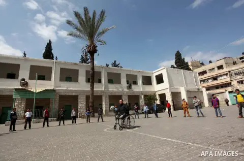 Wheelchair-bound Palestinian student teacher Ahmed al-Sawaferi, 25, who said that he lost his both legs and his left arm in an Israeli air strike in 2008, plays with a student at an elementary school in Gaza City March 1...