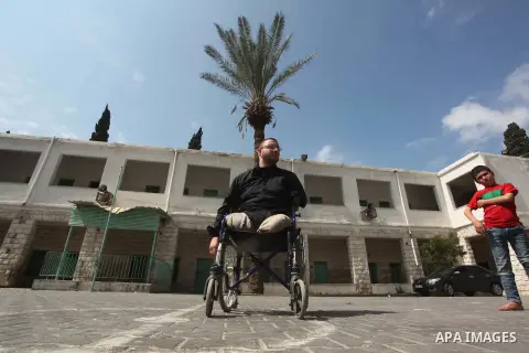 Wheelchair-bound Palestinian student teacher Ahmed al-Sawaferi, 25, who said that he lost his both legs and his left arm in an Israeli air strike in 2008, plays with a student at an elementary school in Gaza City March 1...