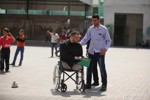 Wheelchair-bound Palestinian student teacher Ahmed al-Sawaferi, 25, who said that he lost his both legs and his left arm in an Israeli air strike in 2008, speaks with his fellows at an elementary school in Gaza City Marc...