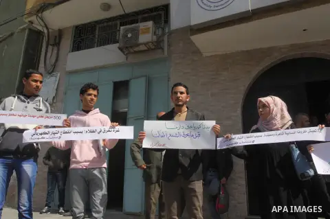 Palestinian youths hold banners during a protest against the power crisis in Gaza strip, in front of Electricity company, in Gaza city, on March 23, 2015. Photo by Mohammed Asad
