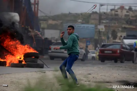 A Palestinian protester hurls stones towards Israeli security forces during clashes following a demonstration against the Israeli settlement of Beit El, in the Jalazon refugee camp near the West Bank city of Ramallah on...