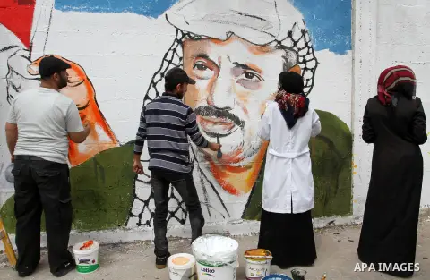 Palestinian artists paint a mural on a wall to mark the Land Day in Rafah in the southern Gaza strip, on March 28, 2015. Photo by Abed Rahim Khatib
