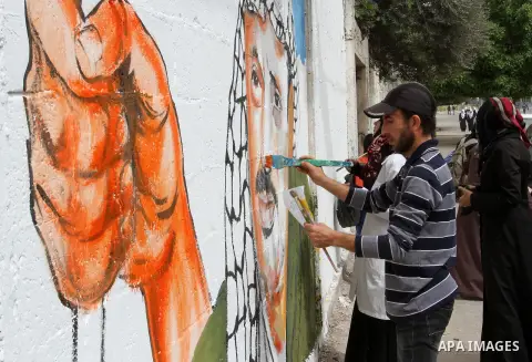 Palestinian artists paint a mural on a wall to mark the Land Day in Rafah in the southern Gaza strip, on March 28, 2015. Photo by Abed Rahim Khatib