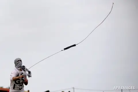 A Palestinian protester uses a sling shot to throw stones towards Israeli security forces during clashes following a protest marking the Palestinian Land Day in the West Bank village of Nabi Saleh near Ramallah, March 28...