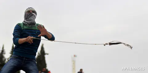 A Palestinian protester uses a sling shot to throw stones towards Israeli security forces during clashes following a protest marking the Palestinian Land Day in the West Bank village of Nabi Saleh near Ramallah, March 28...