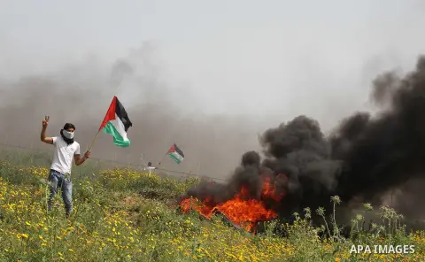A Palestinian man holds a national flag during a rally marking Land day in Khan Younis in the southern Gaza strip, on March 29, 2015. The annual demonstrations mark the deaths of six Arab Israeli protesters at the hands...