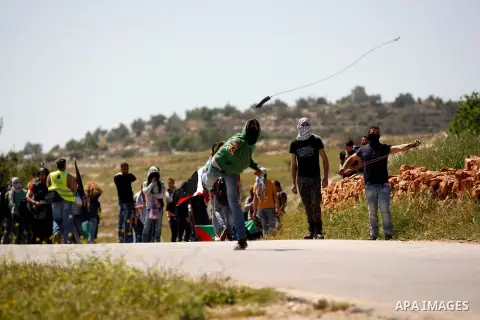 Palestinian protesters use sling shots to hurl stones at Israeli troops during clashes at a weekly against the expansion of Jewish settlements on Palestinian land, in the West Bank village of Nabi Saleh, near Ramallah, A...