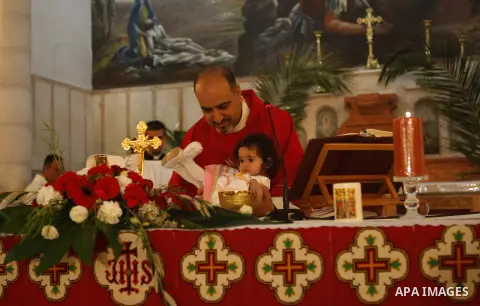 Palestinian Orthodox Christians attend the Palm Sunday mass at Latin Church in the West Bank city of Ramallah on April 5, 2015. Palm Sunday in many Christian churches symbolically marks the biblical account of the entry...