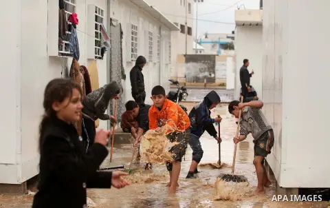 Palestinians, living in containers as temporary replacement for their houses that were destroyed by what witnesses said was Israeli shelling during a 50- day-war in 2014 summer, clean rain water outside their makeshift s...