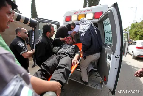 Palestinian medics carry a wounded protester during clashes with Israeli security forces following a protest Palestinian Prisoner's Day and against the expropriation of Palestinian land by Israel in the West Bank village...