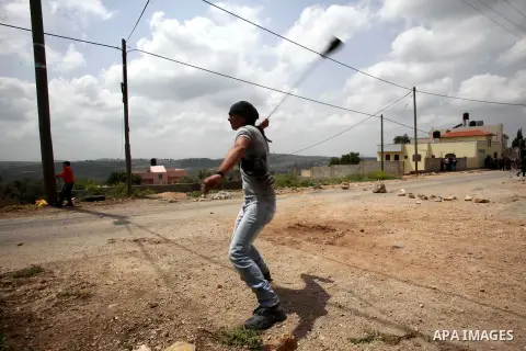 A Palestinian protester uses a sling shot to hurl stones towards Israeli security forces during clashes following a protest Palestinian Prisoner's Day and against the expropriation of Palestinian land by Israel in the We...