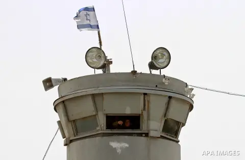 An Israeli soldier looks from a watching tower as Palestinian protesters take part in a demonstration in solidarity with Palestinian prisoners in Israeli jails, at Israeli checkpoint of Hawara, near the West Bank city of...