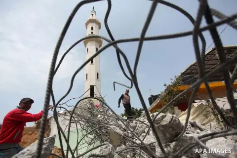 Palestinian workers collect iron bars from the rubbles of houses, that witnesses said were destroyed by Israeli shelling during the 50-day Israeli war in the summer of 2014, in Gaza city on April 22, 2015. According to a...