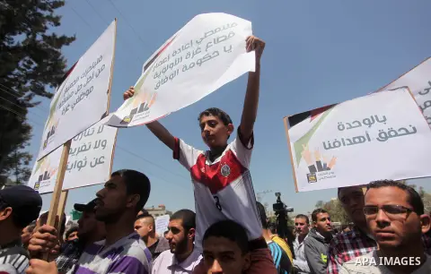 Palestinian youths chant slogans during a protest calling for an end in the political division and opening the Rafah crossing border, in Gaza city, on April 29, 2015. Photo by Ashraf Amra