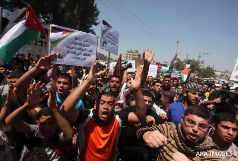 Palestinian youths chant slogans during a protest calling for an end in the political division and opening the Rafah crossing border, in Gaza city, on April 29, 2015. Photo by Ashraf Amra