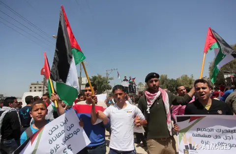 Palestinian youths chant slogans during a protest calling for an end in the political division and opening the Rafah crossing border, in Gaza city, on April 29, 2015. Photo by Ashraf Amra