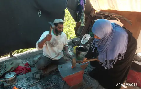 Palestinian blacksmith Ibraheem Mustafa, 40-year-old, with his wife, hammer heated steel to shape a knife, at their small workshop in Gaza city on April 30, 2015. The ILO estimates that the 2014 conflict in Gaza raised u...