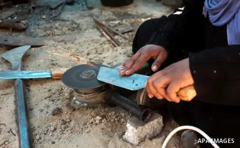 Aysha Ali, the wife of Ibraheem Mustafa, a 40-year-old Palestinian blacksmith, sharpens a handmade knife, at their small workshop in Gaza city on April 30, 2015. The ILO estimates that the 2014 conflict in Gaza raised un...
