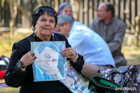 An Egyptian supporter of former President Hosni Mubarak holds his picture during a celebration to mark his 87th birthday, outside Maadi military hospital, near Cairo on May 4, 2015. An Egyptian legal authority on Monday...