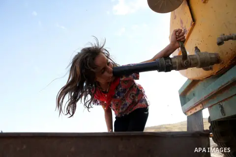 A Palestinian Bedouin girl drinks from a water tank, outside her family's tent in the Jordan valley, near the West Bank town of Tubas, on May 6, 2015. Besieged Palestinian communities in the occupied West Bank's Jordan V...