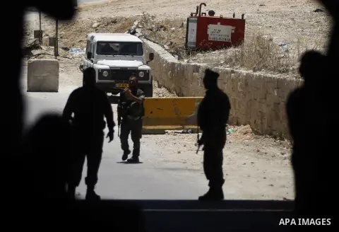 Israeli border policemen stand guard as Palestinian protesters from the East Jerusalem village of al-Zaim, wave Palestinian flags during a protest demanding the opening of the only gate in the separated barrier leading f...