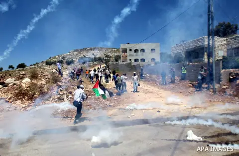 Palestinian protesters run for cover from tear gas fired by Israeli security forces during clashes following a protest against the expropriation of Palestinian land by Israel in the West Bank village of Kafr Qaddum, near...