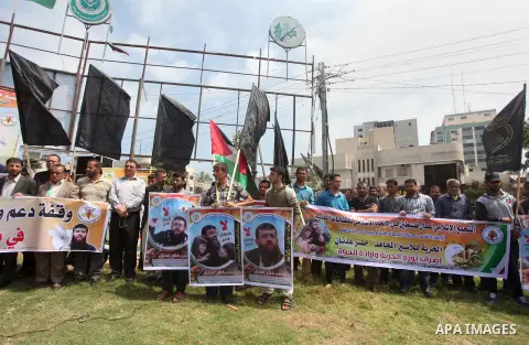 Palestinians holds a picture of Khader Adnan, a senior member of Islamic Jihad jailed in Israel, during a protest calling for the release of Adnan and other prisoners, in Gaza city, on May 10, 2015. Photo by Ashraf Amra