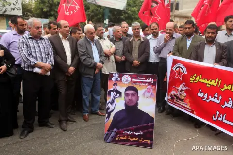 Palestinians hold pictures of prisoners held in Israeli jails, during a protest, in front of Red cross office, in Gaza city, on May 11, 2015. Photo by Ashraf Amra