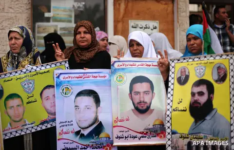 Palestinians hold pictures of prisoners held in Israeli jails, during a protest, in front of Red cross office, in Gaza city, on May 11, 2015. Photo by Ashraf Amra