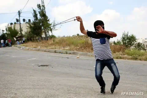 A Palestinian protester hurls stones towards Israeli border police during clashes following a demonstration marking the 67th anniversary of the "Nakba", outside Ofer military prison, near the West Bank city of Ramallah,...