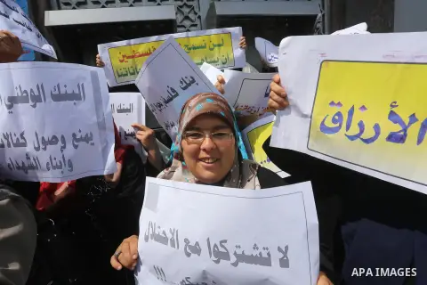 Palestinian relative of orphans and disabled hold banners during a protest against Palestine Bank policy on the closure of the accounts of charities in Gaza city on May 19, 2015. Photo by Mohammed Asad
