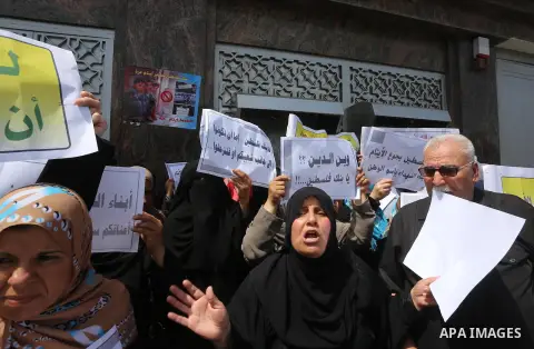 Palestinian relative of orphans and disabled hold banners during a protest against Palestine Bank policy on the closure of the accounts of charities in Gaza city on May 19, 2015. Photo by Mohammed Asad