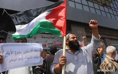 Palestinian relative of orphans and disabled hold banners during a protest against Palestine Bank policy on the closure of the accounts of charities in Gaza city on May 19, 2015. Photo by Mohammed Asad