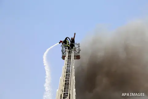 Egyptian firefighters ride their vehicle as smoke billows from a fire broke out at the Customs Authority building, in downtown Cairo, on May 20, 2015. Photo by Amr Sayed