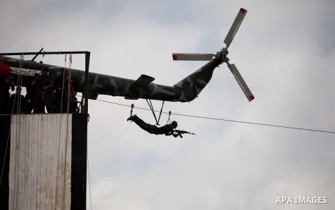 A member of the Palestinian security forces descends down a zip-line during a military training graduation ceremony in Gaza City on May 21, 2015. Photo by Ashraf Amra